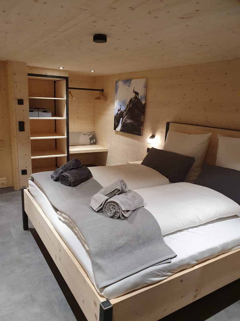 Bild von Zimmer mit Holzverkleidung, Doppelbett und offenem Kleiderschrank