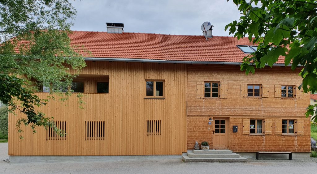 Bild eines sanierten Bauernhauses mit Schindeln und Holzschild